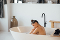 Young woman hugs her legs while sitting in the bath - PhotoDune Item for Sale