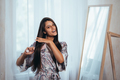 Beautiful young woman combing hair in front of her mirror. - PhotoDune Item for Sale