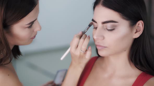 Artist Applies Eye Shadow on the Face of Young Beautiful Brunette Woman
