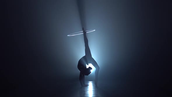 Gymnast Tricks with Hoops on Her Hands and Lifts Her Leg in the Air