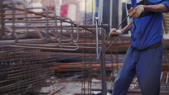 builder folds metal reinforcement at construction site