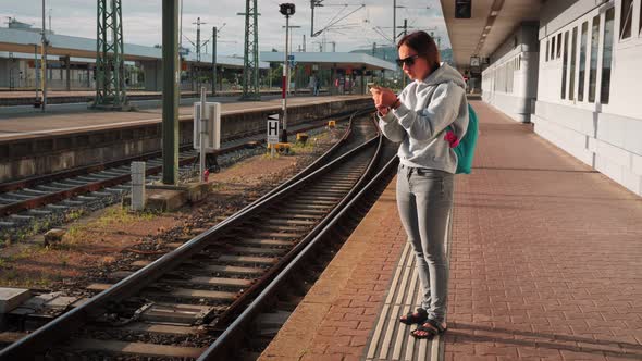 Woman waiting for train on empty railway platform. 