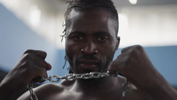 Headshot Portrait of Confident Serious Strong Man Stretching Metal Chain with Hands Looking at