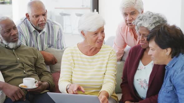 Happy senior diverse people talking and using laptop at retirement home