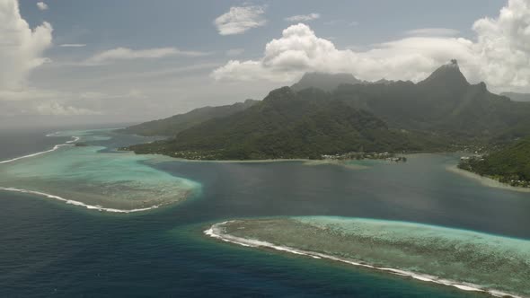 Aerial dolly left shot of Mo'orea island surrounded by barrier reef in French Polynesia