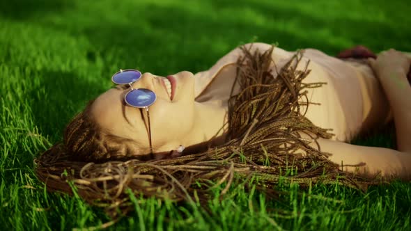 Trendy Hipster Girl with Dreads Relaxing on the Grass in Park