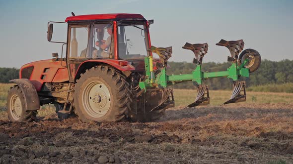 Tractor plowing land. View of red tractor in the agricultural field