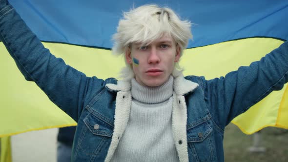 Caucasian man holding Ukrainian flag stretched and looking at camera. Shot with RED helium camera in