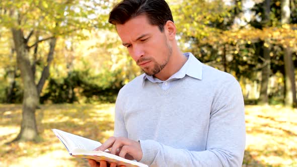 Young Man Stands in the Woods and with Interest Reads a Book