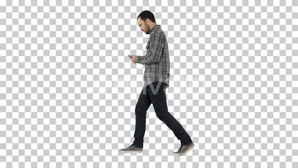 Young smart casual man walking and reading message on cell