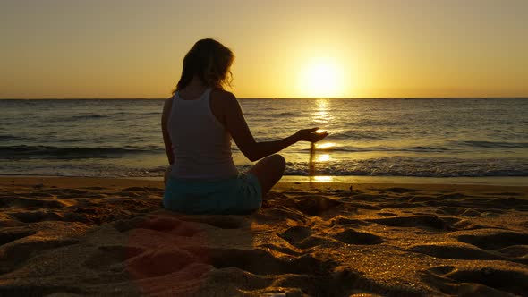 Woman Sitting on Beach at Golden Scenic Sunset Shining at Ocean Grain of Sands