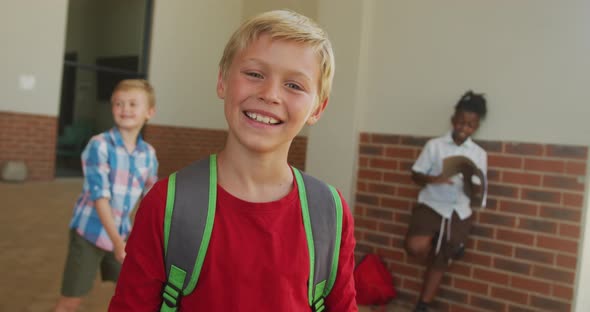 Video of happy caucasian boy standing in front of school