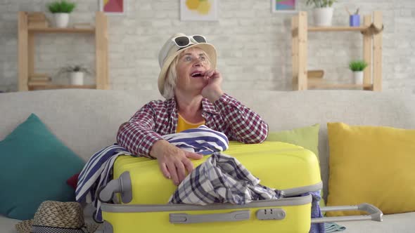Thoughtful Smiling Woman Pensioner Suitcase His Hands Sitting Couch