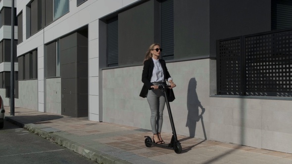 Woman traveling on electric scooter on the sidewalk