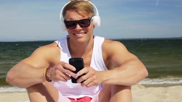 Happy Man with Smartphone and Headphones on Beach