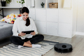 Girl using tablet, robot vacuum cleaner is cleaning floor in the living room - PhotoDune Item for Sale