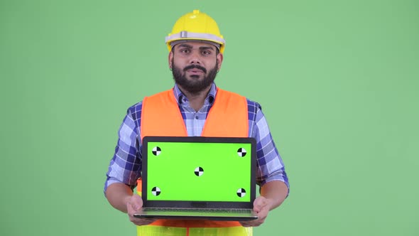 Happy Young Overweight Bearded Indian Man Construction Worker Talking While Showing Laptop