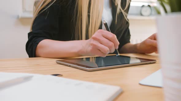 Business Women Working on Tablet in Office. Attractive Blond Female with Long Hair in Elegant Suit