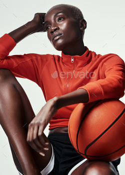 Studio shot of an attractive young woman playing basketball against a grey background