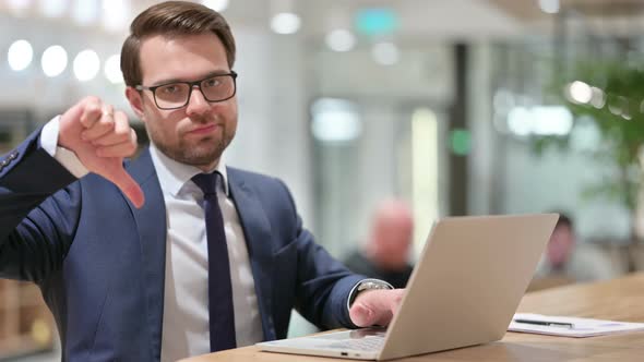 Young Businessman with Laptop Showing Thumbs Down 