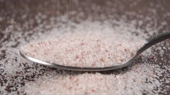 Himalayan pink salt fills a teaspoon in slow motion