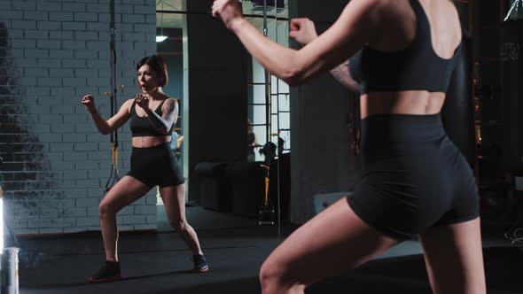 Badass Tattooed Woman Exercising Karate Moves in Front of a Mirror