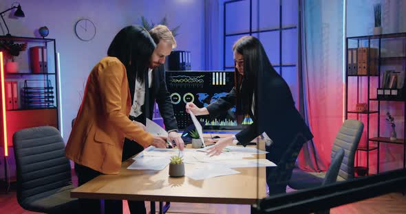 Business Team of Male and Female Office Workers Viewing Paper Reports on the Table