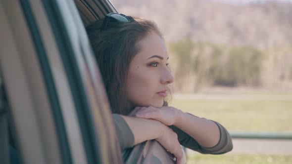 Brunette with Sunglasses on Head Looks Out of Modern Car