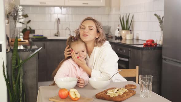 Mother Hugs Her Little Daughter Sitting Table Kitchen She Praises Her Child Eating Porridge Mother