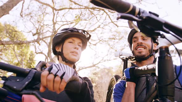 Mountain biking couple carrying bicycle and interacting with each other