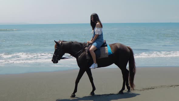 Cute Chinese Teenager Rides a Horse On The Beach In Bali