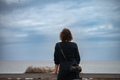 Rear view of woman standing and watching the ocean - PhotoDune Item for Sale