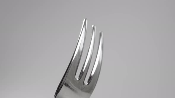 Shiny empty fork on a white gray background close-up. Macro