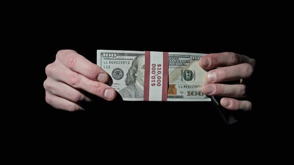 Stack of 10000 American Dollars in Bundle in Male Hands on Black Background