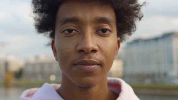 Close Up Portrait of Cheerful Afro Guy Putting on and Off Safety Mask Standing Outdoors