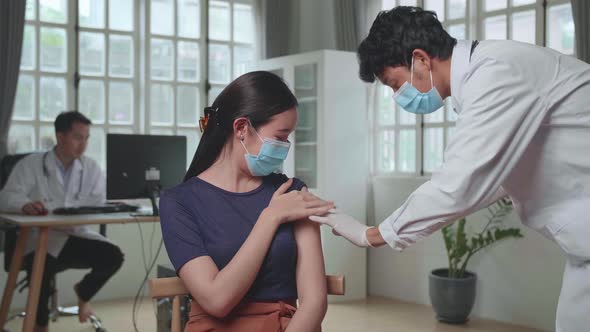 Doctor In Safety Gloves And Protective Mask Is Making A Vaccine Injection To A Female Patient