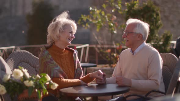 Healthy senior couple holding hands in the outdoor cafe on a sunny autumn day