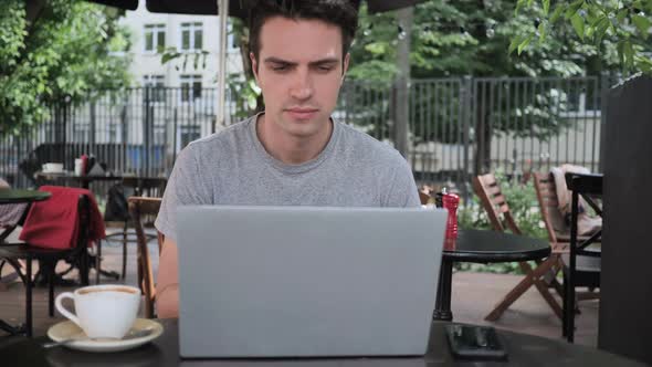 Pensive Man Thinking and Working on Laptop Sitting in Cafe Terrace