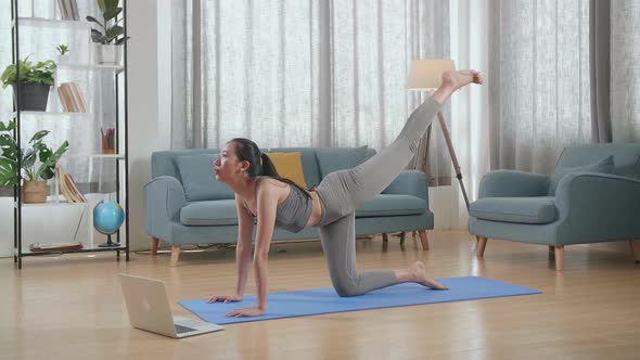 Young Asian Athletic Female Exercising, Stretching And Practicing Yoga At Home With Online Coach