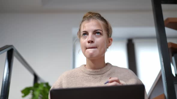 Front View Cute Teenage Girl Thinking Typing on Laptop Keyboard Sitting Indoors at Home