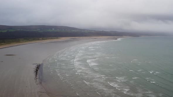 AERIAL: High flight across overcast Beach with crashing waves, Oxwich, 4K Drone