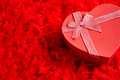 Heart shaped boxed gift, placed on red feathers background - PhotoDune Item for Sale