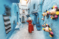 Young woman with red dress visiting the blue city Chefchaouen, Marocco  - PhotoDune Item for Sale