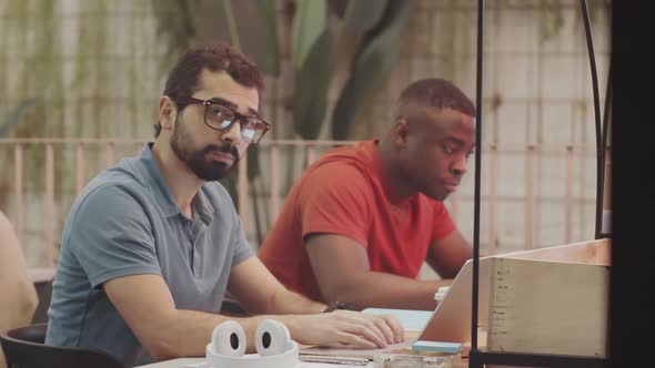 Middle Eastern Man Working on Laptop and Posing for Camera