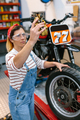 Mechanic woman checking motorbike caliper brake system on factory - PhotoDune Item for Sale