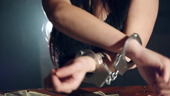 Illegal money and handcuffs. Woman trying to free herself
