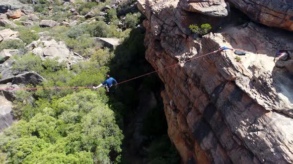 Male highliner sitting on a rope over rocky mountains 4k