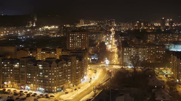 Illuminated city streets at night, road traffic and residential flats