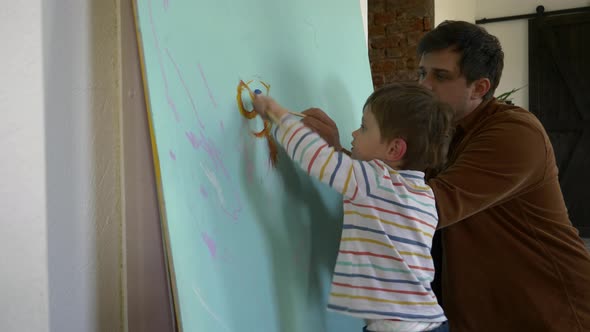 father and son paint on the wall during quarantine