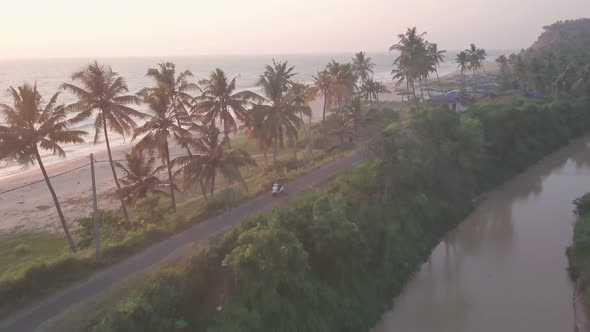 A Motorcycle Crossing A Small Concrete Road Next To The Varkala Beach Under The Sunset In Kerala, In